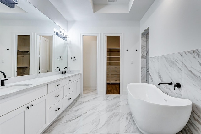 bathroom featuring vanity, a bath, and tile walls