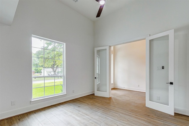 unfurnished bedroom featuring multiple windows, ceiling fan, french doors, and high vaulted ceiling