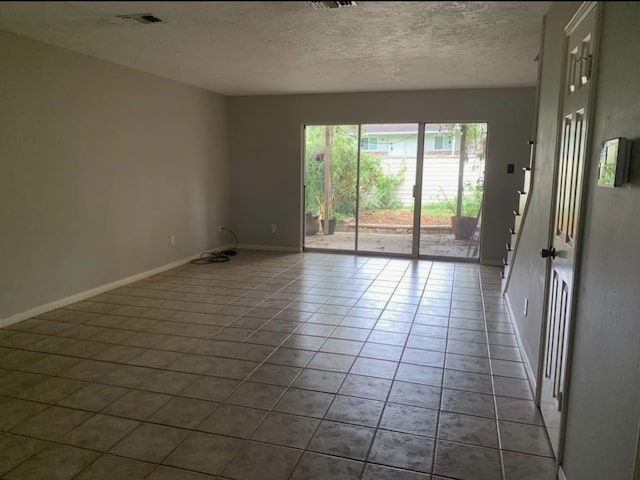 tiled empty room with a textured ceiling