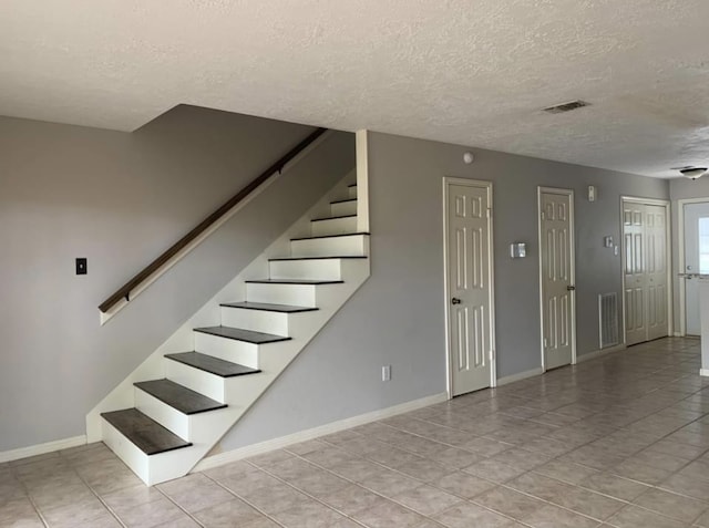 stairway featuring tile patterned flooring and a textured ceiling