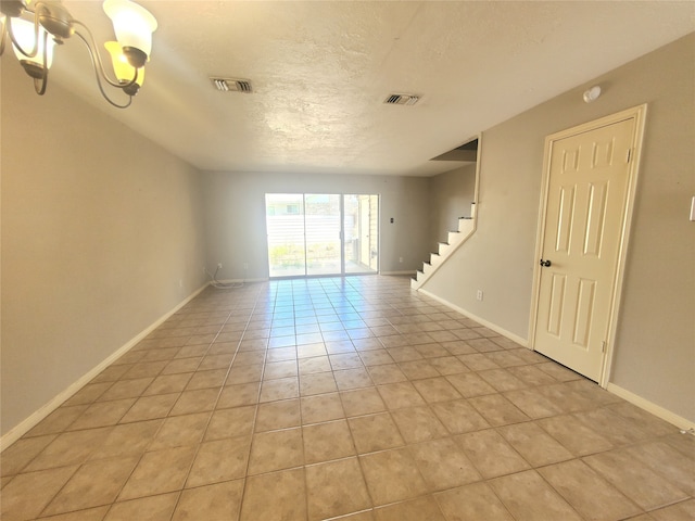 unfurnished room featuring baseboards, stairway, light tile patterned floors, a textured ceiling, and visible vents