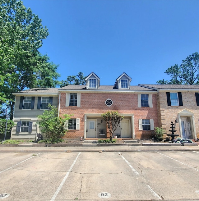 townhome / multi-family property featuring uncovered parking and brick siding