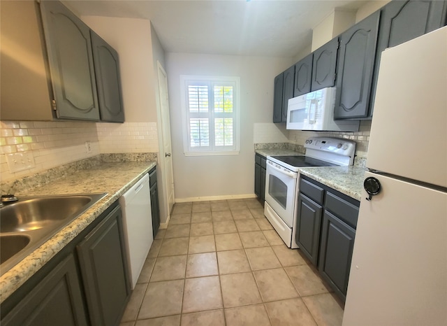 kitchen featuring baseboards, white appliances, light countertops, decorative backsplash, and a sink