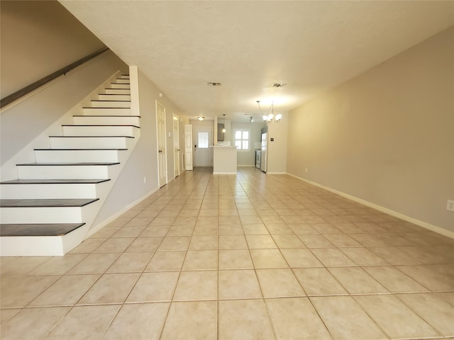 unfurnished living room with light tile patterned floors, baseboards, visible vents, an inviting chandelier, and stairs