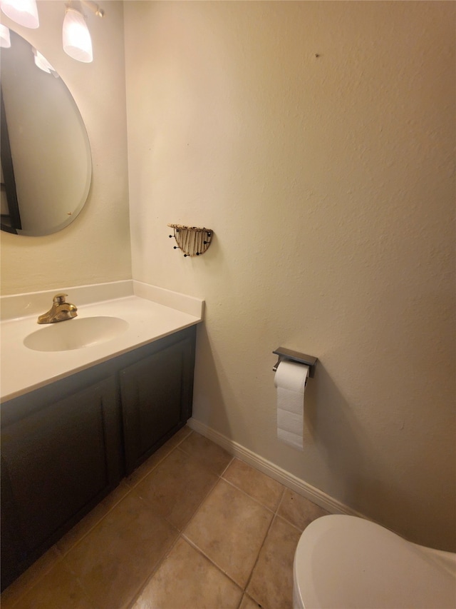 bathroom with tile patterned flooring, vanity, baseboards, and toilet
