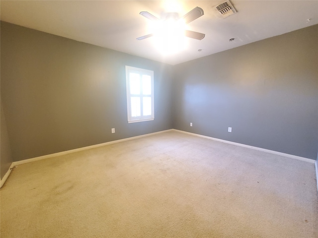 carpeted spare room with ceiling fan, baseboards, and visible vents