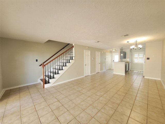 2030 Plantation Dr Unit B-2, Conroe, TX 77301 - unfurnished living room with light tile patterned floors, a chandelier, stairway, baseboards, and a textured ceiling