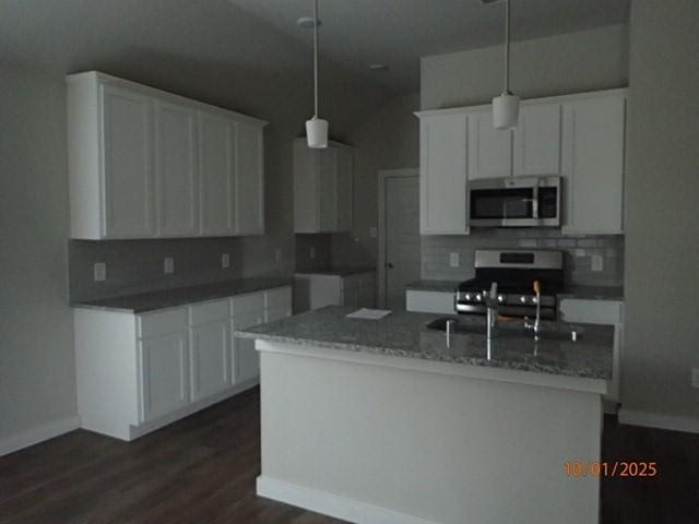 kitchen featuring a center island with sink, lofted ceiling, white cabinetry, and stainless steel appliances