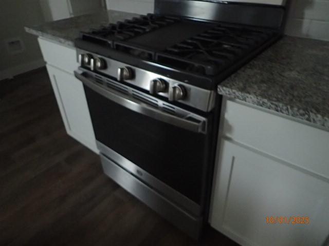 kitchen featuring high end range, dark hardwood / wood-style flooring, white cabinets, and light stone counters