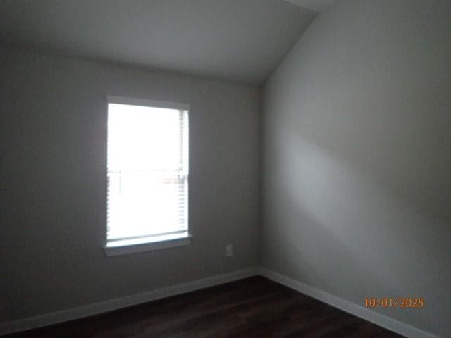 spare room with dark hardwood / wood-style floors and lofted ceiling