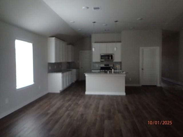 kitchen featuring white cabinets, stove, dark hardwood / wood-style flooring, and a kitchen island with sink