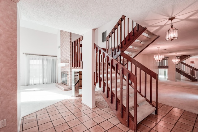 staircase featuring carpet flooring, a fireplace, a chandelier, and a textured ceiling