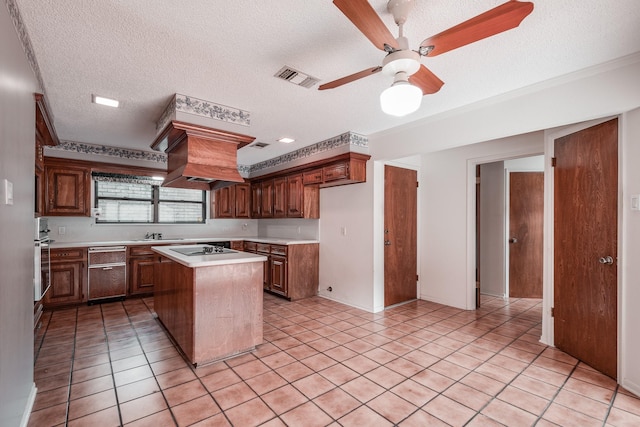 kitchen with oven, a textured ceiling, light tile patterned flooring, ceiling fan, and a kitchen island