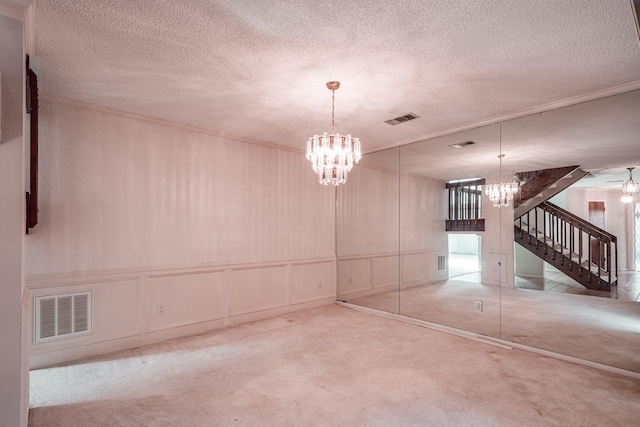 carpeted spare room featuring a notable chandelier and a textured ceiling