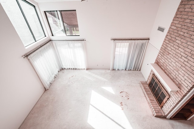 unfurnished living room with a high ceiling and a brick fireplace