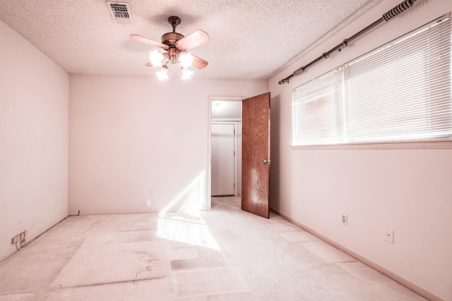 unfurnished room featuring a textured ceiling, ceiling fan, and light carpet