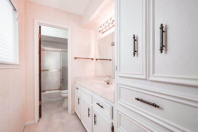 full bathroom featuring toilet, combined bath / shower with glass door, a wealth of natural light, and vanity