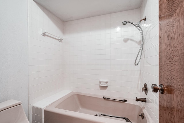 bathroom featuring toilet and tiled shower / bath