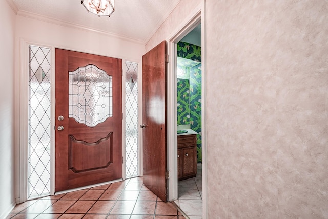 tiled entrance foyer featuring a textured ceiling and crown molding