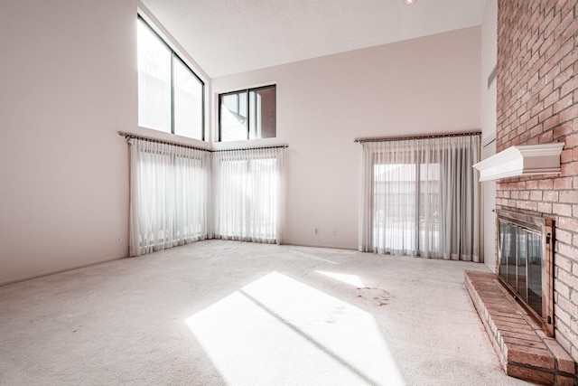 unfurnished living room featuring a high ceiling, carpet flooring, and a fireplace