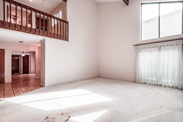 unfurnished living room featuring ceiling fan, a towering ceiling, and carpet flooring