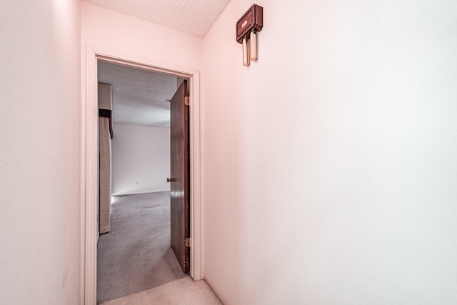 hallway featuring a textured ceiling and light carpet