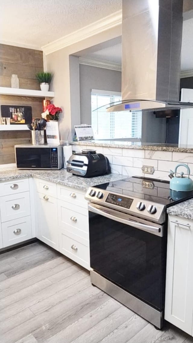 kitchen with white cabinetry, stainless steel electric range oven, light stone countertops, island exhaust hood, and a textured ceiling