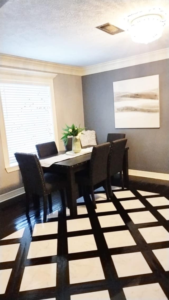 dining space featuring ornamental molding and a textured ceiling