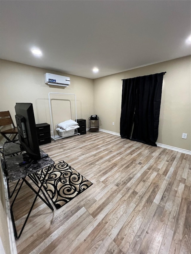 basement with a wall mounted AC and light hardwood / wood-style floors