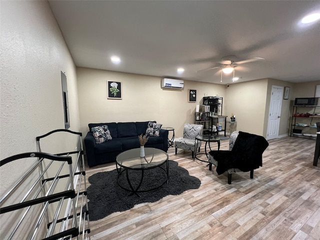 living room with an AC wall unit, ceiling fan, and light hardwood / wood-style flooring