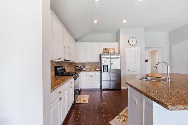 kitchen with stainless steel fridge, black range with gas stovetop, sink, white cabinets, and an island with sink