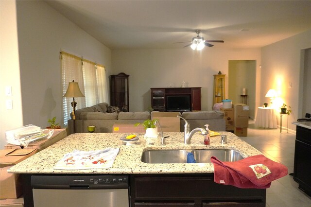 kitchen featuring light stone counters, sink, dishwasher, and a center island with sink