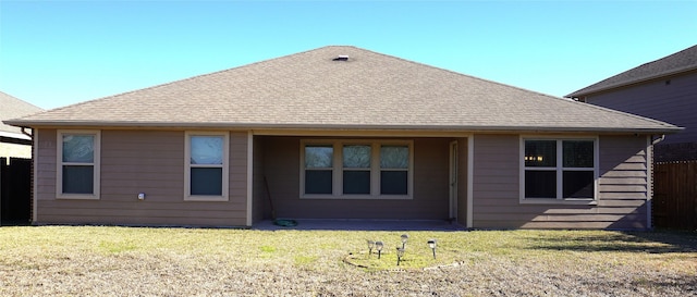 rear view of house featuring a yard and fence