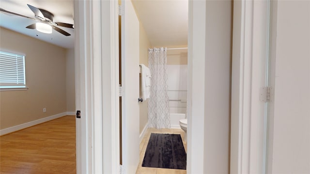 bathroom with ceiling fan, wood-type flooring, shower / tub combo, and toilet