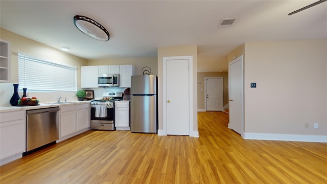 kitchen with light hardwood / wood-style flooring, white cabinets, stainless steel appliances, and sink