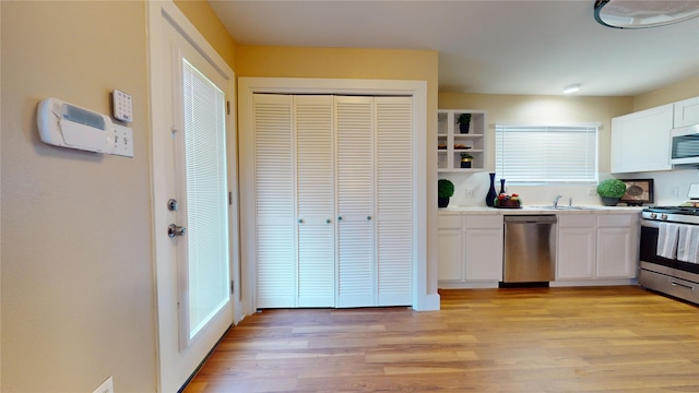 kitchen with sink, white cabinetry, stainless steel appliances, and light hardwood / wood-style flooring