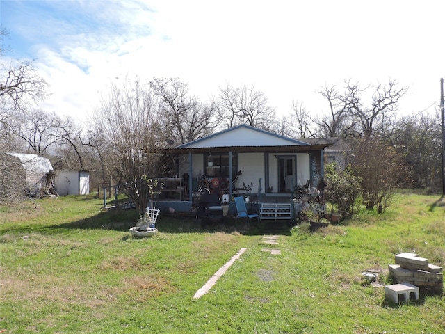 back of property featuring a porch, a storage shed, and a yard