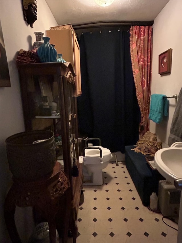 bathroom with a shower with curtain, sink, a textured ceiling, and toilet