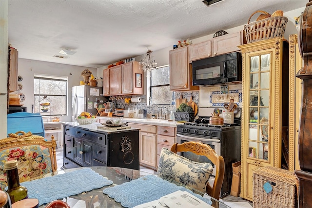 kitchen with backsplash, sink, light brown cabinets, stainless steel appliances, and a chandelier