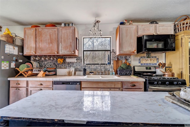 kitchen with stainless steel appliances, tile countertops, pendant lighting, and sink