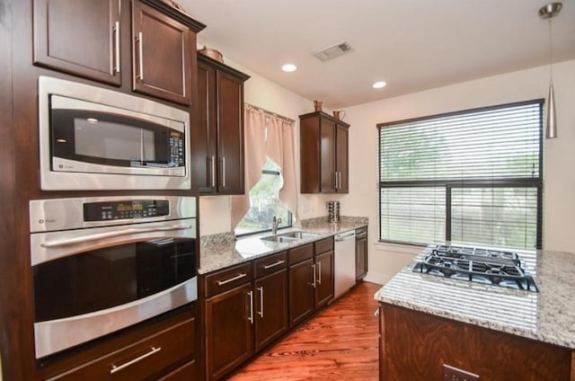 kitchen featuring sink, light stone countertops, a wealth of natural light, and appliances with stainless steel finishes