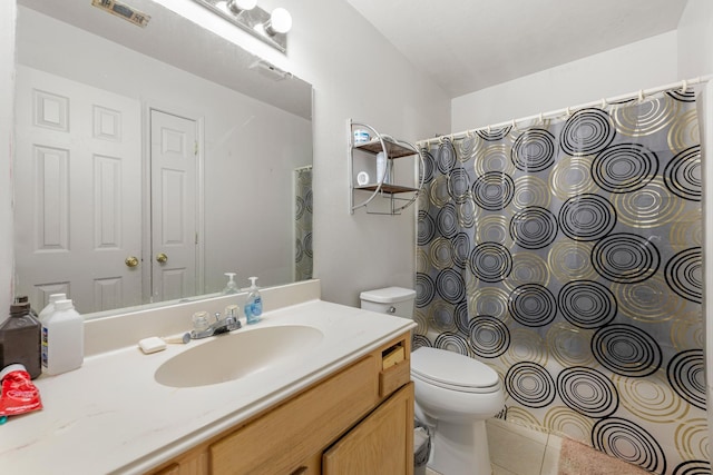 bathroom with toilet, vanity, and tile patterned floors