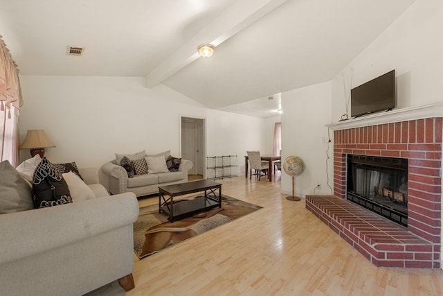 living room with a brick fireplace, light hardwood / wood-style flooring, and vaulted ceiling with beams