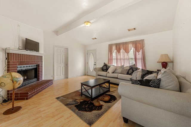 living room featuring lofted ceiling with beams, a brick fireplace, and hardwood / wood-style flooring