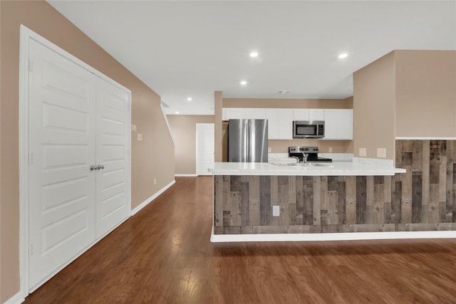 kitchen featuring kitchen peninsula, white cabinetry, dark hardwood / wood-style flooring, and appliances with stainless steel finishes