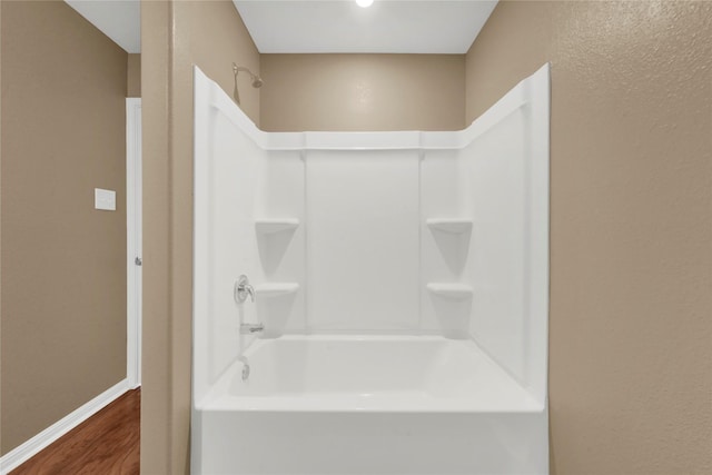 bathroom featuring wood-type flooring and bathtub / shower combination