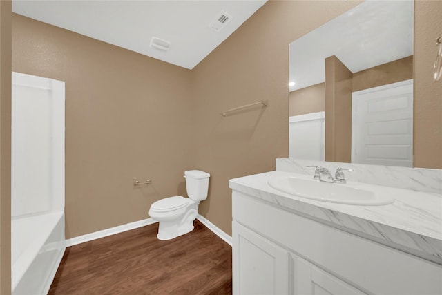 bathroom with a tub to relax in, vanity, hardwood / wood-style flooring, and toilet