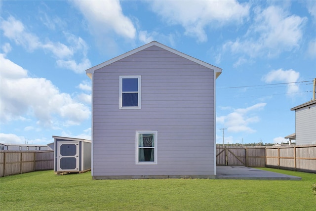 rear view of property with a yard, a patio, and a storage unit