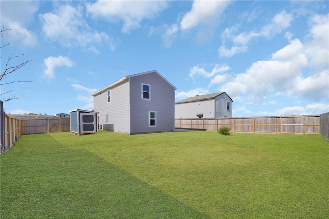 rear view of house with central air condition unit, a storage shed, and a lawn