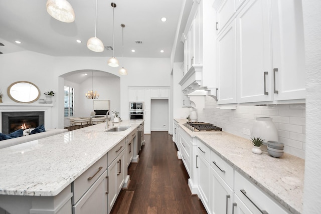 kitchen with light stone countertops, sink, pendant lighting, a spacious island, and white cabinets